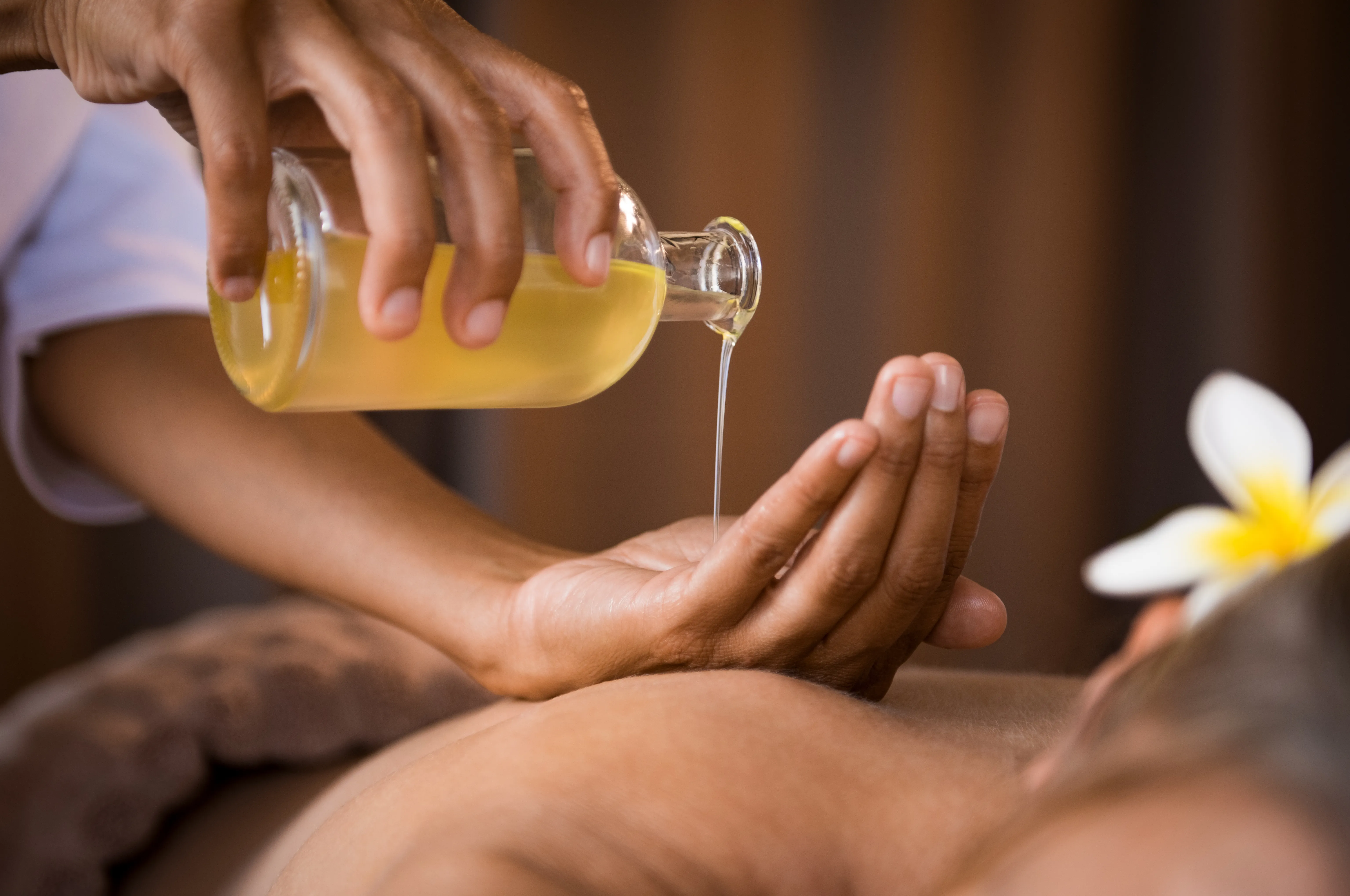 Warmes Massageöl wird für eine wohltuende Massage in die Hände gegossen